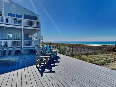 a row of chairs sitting on a deck near the beach at Charline Beachside Villa in Panama City Beach