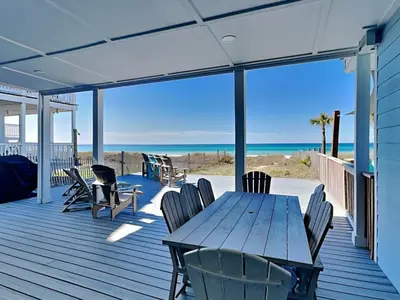 a wooden table and chairs on a deck with the beach at Charline Beachside Villa in Panama City Beach