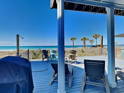 a deck with chairs and tables and the beach at Charline Beachside Villa in Panama City Beach