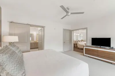 a white bedroom with a bed and a flat screen tv at The Pointe Unit 326 by 30A Escapes in Rosemary Beach