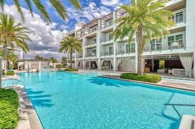 a swimming pool in front of a building with palm trees at Texas Two Step by 30A Escapes in Rosemary Beach