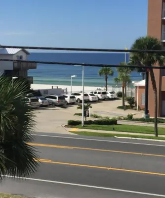 a street with cars parked in a parking lot next to the beach at Beach Place Seconds to Beach 23 in Panama City Beach