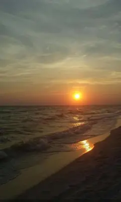 a sunset on the beach with the ocean at Beach Place Seconds to Beach 23 in Panama City Beach