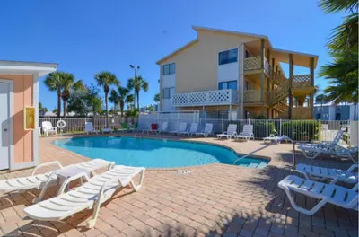 a swimming pool with lounge chairs and a house at Beach Place Seconds to Beach 23 in Panama City Beach