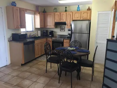 a kitchen with a table with chairs and a refrigerator at Beach Place Seconds to Beach 23 in Panama City Beach