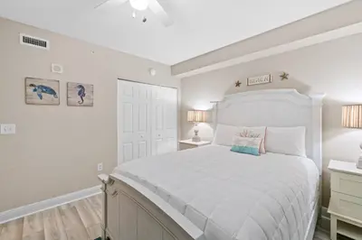 a white bedroom with a white bed and a white door at Emerald Beach #1236 by Book That Condo in Panama City Beach