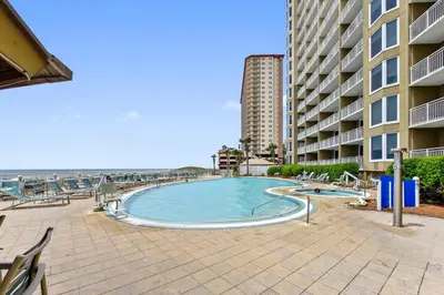 a swimming pool next to a building and the beach at Emerald Beach #1236 by Book That Condo in Panama City Beach
