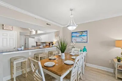 a kitchen and dining room with a wooden table and chairs at Emerald Beach #1236 by Book That Condo in Panama City Beach