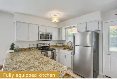 a kitchen with white cabinets and a stainless steel refrigerator at Estrella del Mar in Panama City Beach