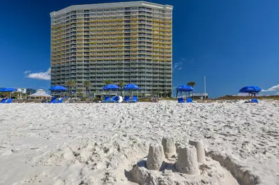 a beach with blue chairs and umbrellas and a building at Boardwalk Beach Resort #1206 by Book That Condo in Panama City Beach