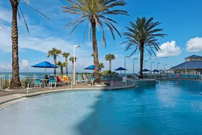 a large swimming pool with palm trees and chairs at Boardwalk 2005 in Panama City Beach