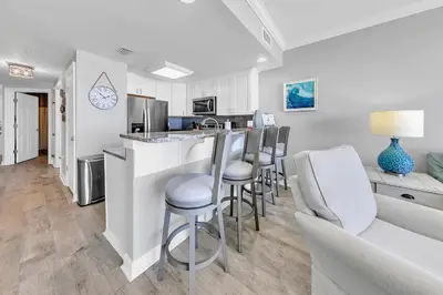 a kitchen and living room with a bar and chairs at Boardwalk 2005 in Panama City Beach