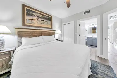 a bedroom with a large white bed and a bathroom at Boardwalk 2005 in Panama City Beach