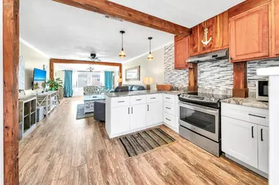 a large kitchen with white cabinets and wood floors at Misty Harbour 7 in Panama City Beach