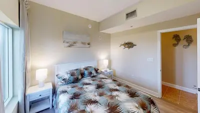 a bedroom with a bed and two lamps and a window at Tidewater 100 in Panama City Beach