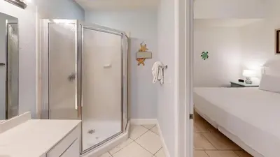 a white bathroom with a shower and a bed at Tidewater 2714 in Panama City Beach