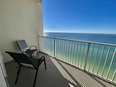 a chair on a balcony with a view of the ocean at Tidewater 2714 in Panama City Beach