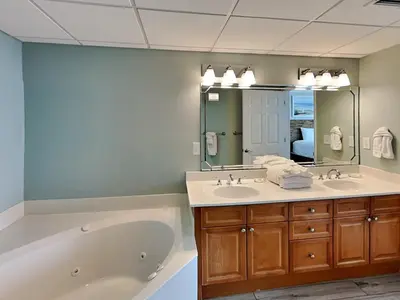 a bathroom with a tub and a sink and a mirror at Emerald Beach #830 in Panama City Beach