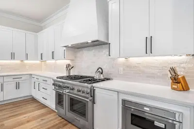 a white kitchen with a stove and white cabinets at 30A Sunset in Santa Rosa Beach