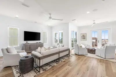 a living room with white furniture and a flat screen tv at 30A Sunset in Santa Rosa Beach