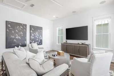 a living room with white furniture and a flat screen tv at 30A Sunset in Santa Rosa Beach