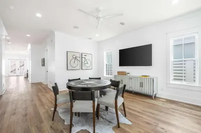 a dining room with a table and chairs and a flat screen tv at 30A Sunset in Santa Rosa Beach