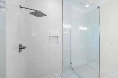 a shower with a glass door and white tiles at 30A Sunrise in Santa Rosa Beach