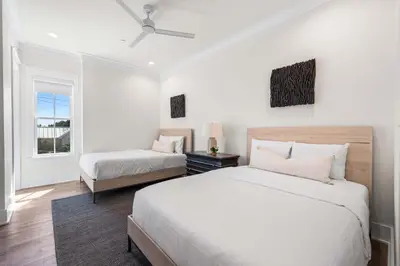 a white bedroom with two beds and a window at 30A Sunrise in Santa Rosa Beach
