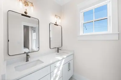 a white bathroom with two sinks and a window at 30A Sunrise in Santa Rosa Beach