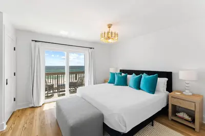 a bedroom with a bed with blue pillows and a window at Howdy Beach by 30A Escapes in Panama City Beach