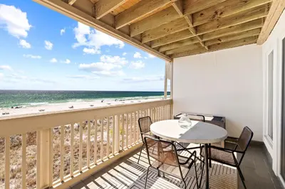 a balcony with a table and chairs and a view of the beach at Howdy Beach by 30A Escapes in Panama City Beach