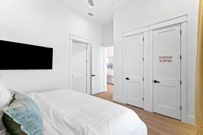 a white bedroom with white cabinets and a bed at Jewel of Oleander by 30A Escapes in Panama City Beach
