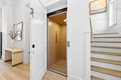 a hallway with white walls and stairs with a sliding door at Jewel of Oleander by 30A Escapes in Panama City Beach