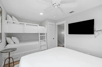 a white bedroom with a bed and a flat screen tv at Ramsgate Harbour #5 by 30A Escapes in Panama City Beach