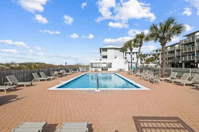 a swimming pool with chairs and trees and a building at Ramsgate Harbour #5 by 30A Escapes in Panama City Beach