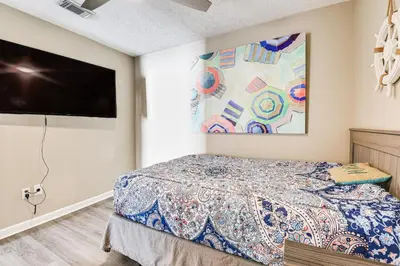 a bedroom with a bed and a flat screen tv at Charming PCB Home about 1 Mi to Beach Access! in Panama City Beach