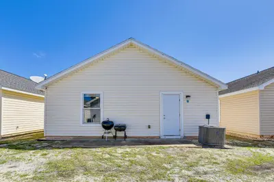 a white house with two trash cans in front of it at Charming PCB Home about 1 Mi to Beach Access! in Panama City Beach