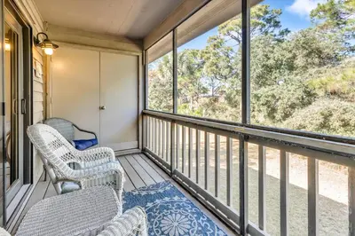 a screened in porch with chairs and windows at Somewhere in the Sun in Santa Rosa Beach