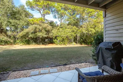 a porch with chairs and a yard with trees at Somewhere in the Sun in Santa Rosa Beach