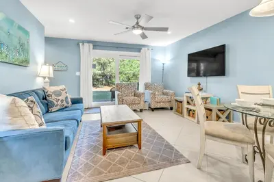 a living room with a blue couch and a table at Somewhere in the Sun in Santa Rosa Beach