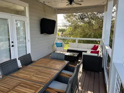 a patio with a table and chairs on a porch at Barefoot Dreams! in Panama City Beach
