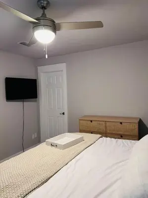 a bedroom with a white bed with a ceiling fan at Barefoot Dreams! in Panama City Beach