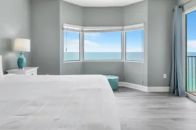 a white bedroom with a large bed and windows at Tidewater 2308 by Emerald Coast Retreats in Panama City Beach