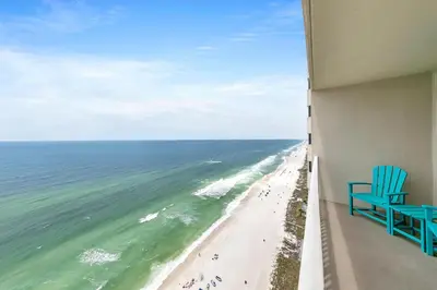 a blue chair sitting on a balcony looking out at the beach at Tidewater 2308 by Emerald Coast Retreats in Panama City Beach