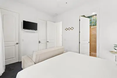 a white bedroom with a bed and a chair at Beach House - Sea La Vie by Panhandle Getaways in Panama City Beach