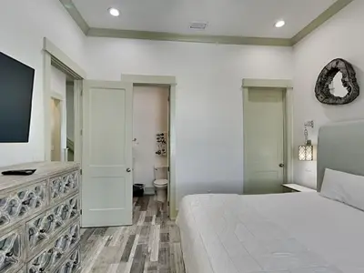 a white bedroom with a bed and a tv at Resting Beach Face in Panama City Beach