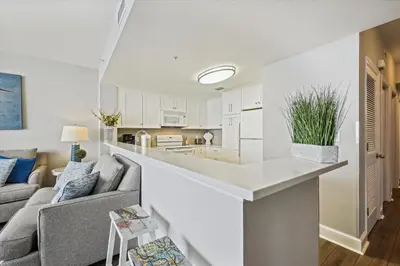 a white living room with a couch and a kitchen at Majestic Beach Resort 1411-1 by Book That Condo in Panama City Beach