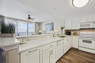 a kitchen with white cabinets and a large window at Majestic Beach Resort 1411-1 by Book That Condo in Panama City Beach