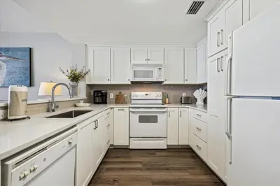a white kitchen with white appliances and white cabinets at Majestic Beach Resort 1411-1 by Book That Condo in Panama City Beach
