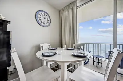 a dining room with a table and a clock on the wall at Majestic Beach Resort 1411-1 by Book That Condo in Panama City Beach
